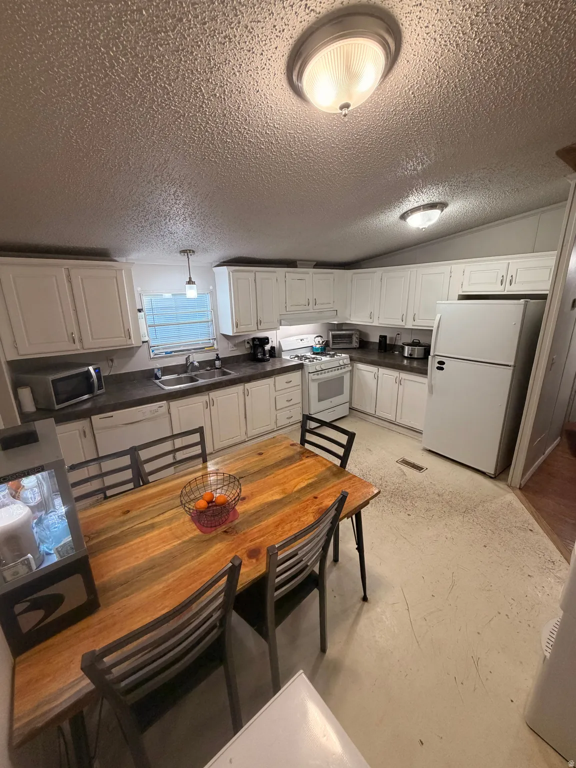 Kitchen area featuring extensive white cabinetry, dark countertops, and a built-in double basin sink with a single-handle faucet