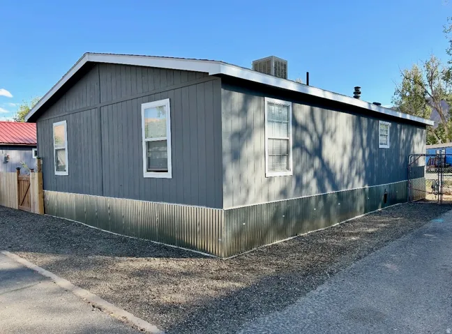 Manufactured home with gray vertical siding and white trim windows