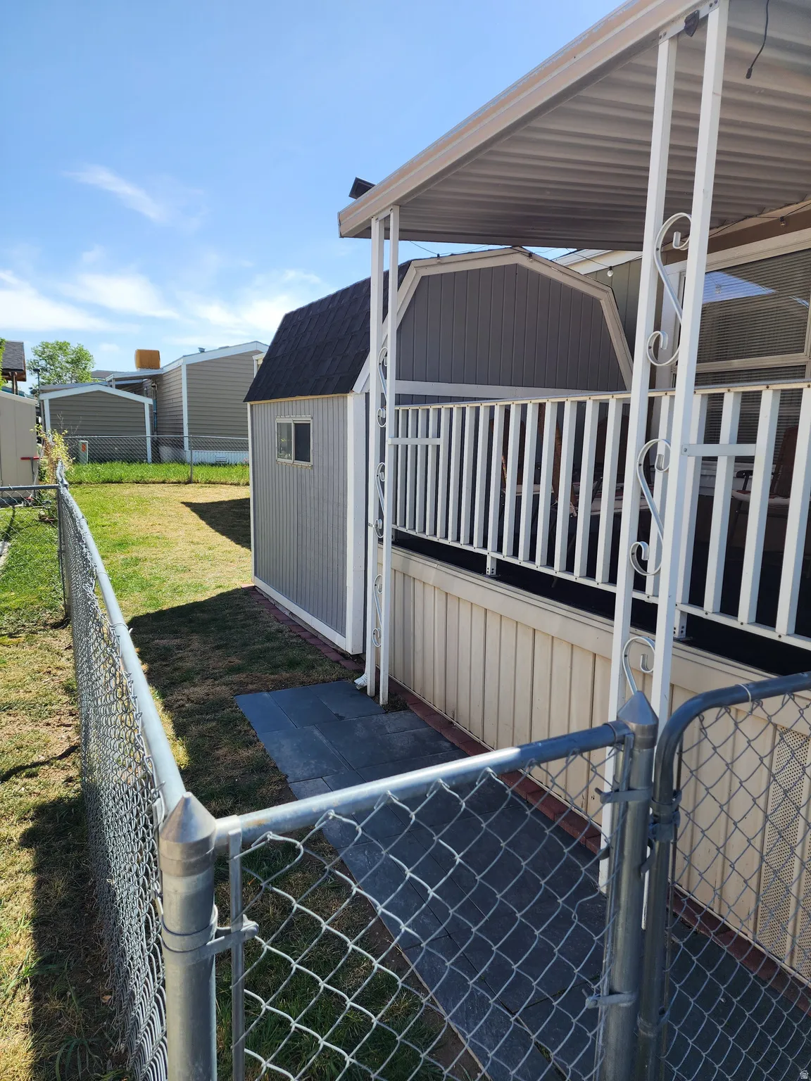 Side yard featuring a chain-link fence, grassy area, and a detached storage shed with a barn-style roof