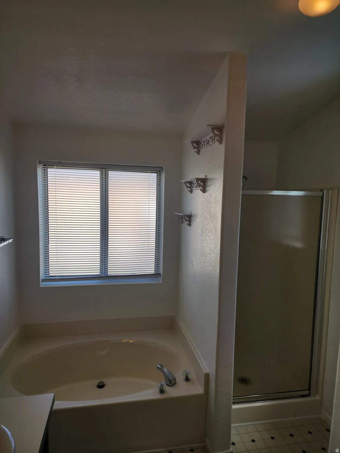 Soaking tub with chrome fixtures, adjacent to a glass-enclosed shower