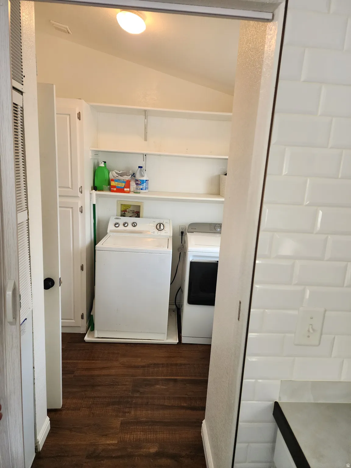 Laundry area featuring wood-finish flooring, built-in shelving, white cabinetry, and a ceiling-mounted light fixture