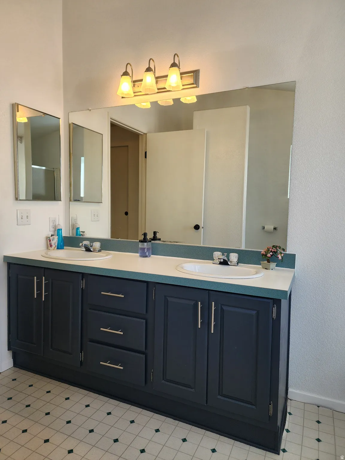 Double vanity featuring dual undermount sinks with chrome fixtures, deep blue cabinetry, and a full-width mirror