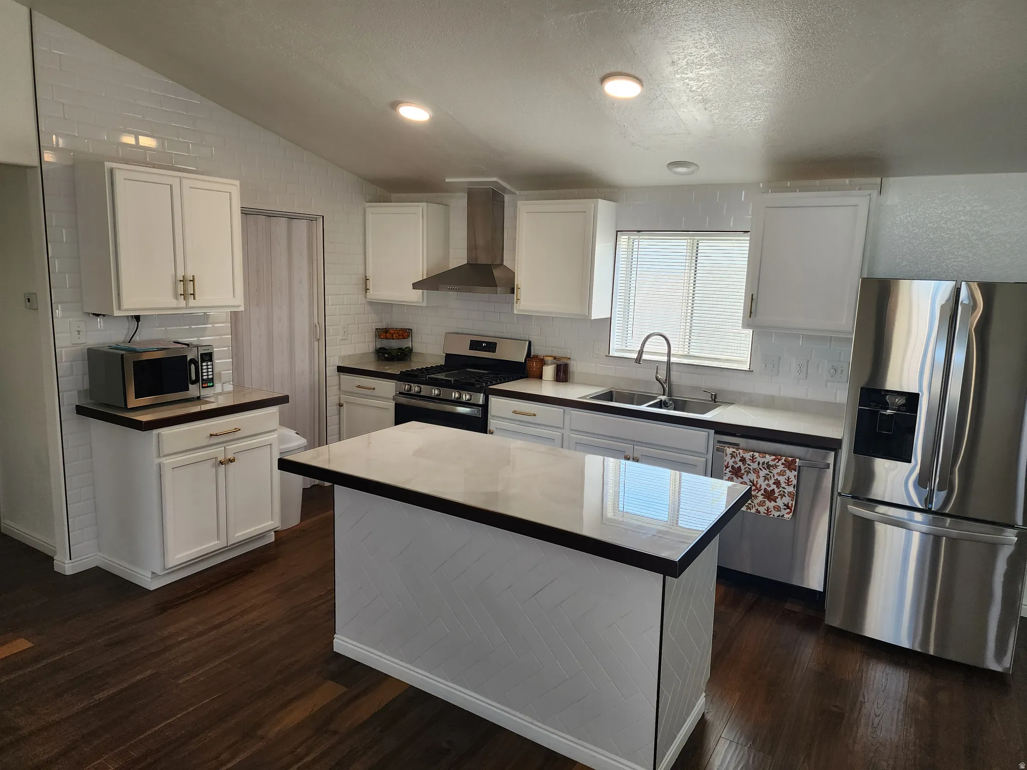 Modern kitchen featuring dark wood-finish flooring, white cabinetry, and stainless steel appliances