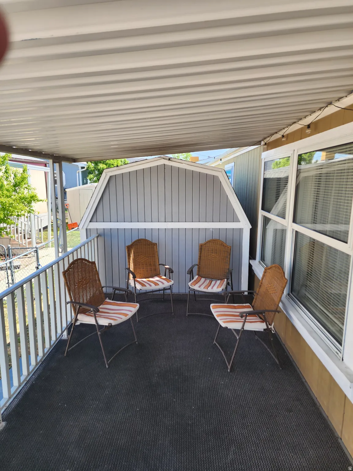 Covered patio with a corrugated metal ceiling, textured flooring, and a white railing