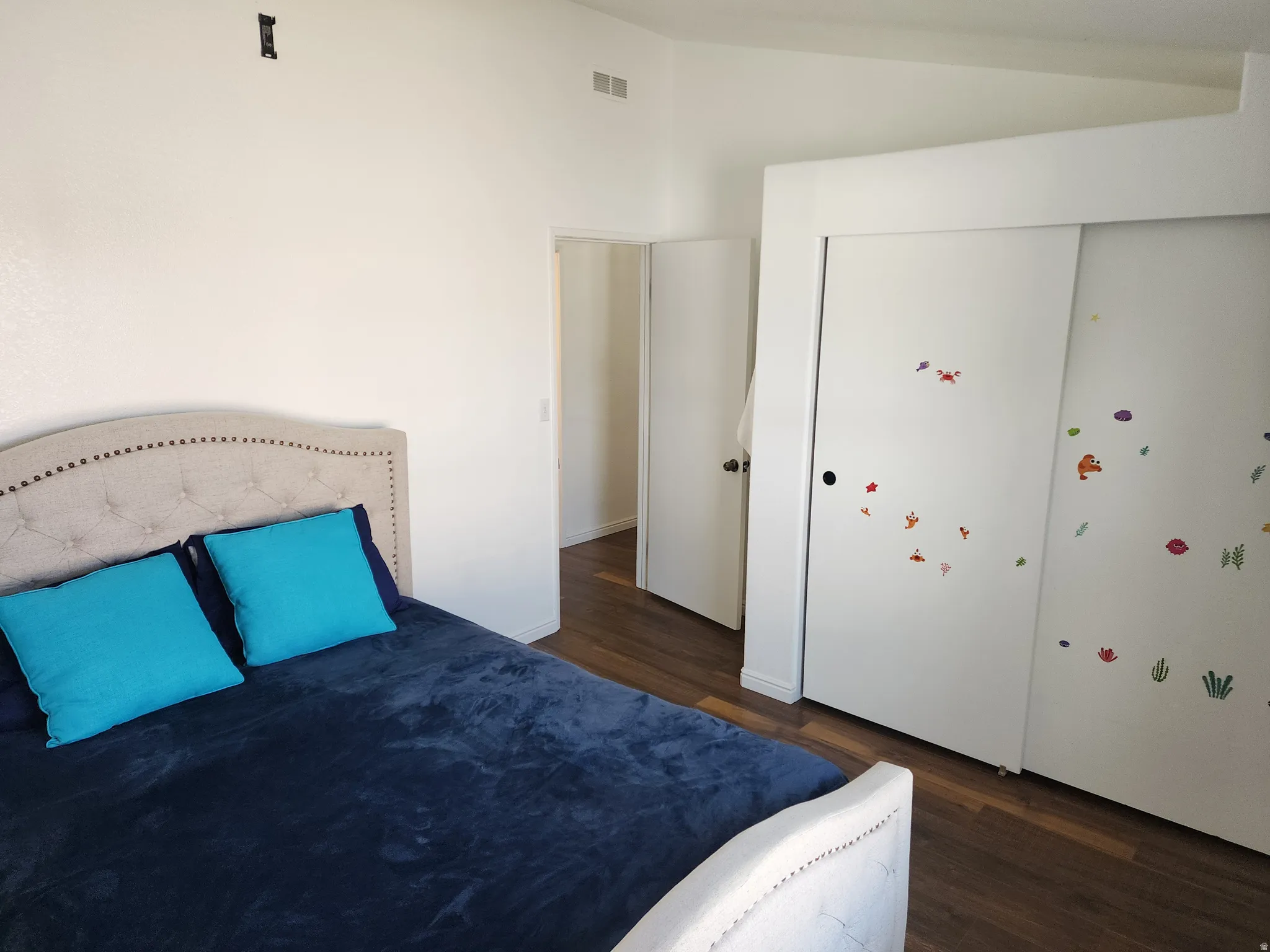 Bedroom featuring wood-finish flooring, white walls, and a built-in closet with sliding doors