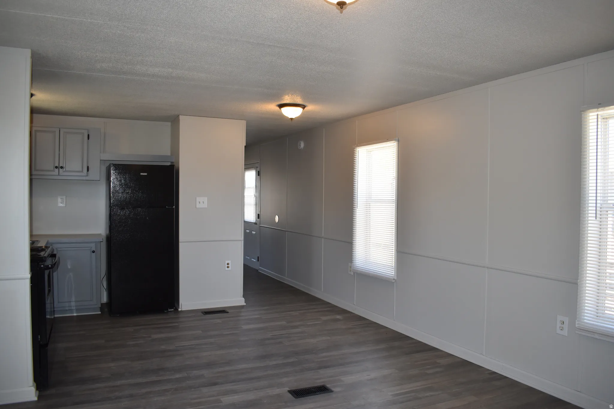 Spacious room featuring wood-finish flooring and two distinct windows