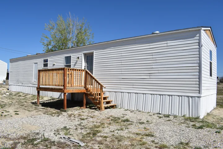 Single-story residence featuring white horizontal siding and a matching vertical skirting