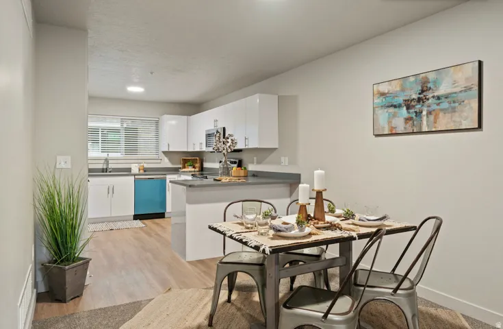Open-concept kitchen and dining area featuring light wood-finish flooring, white cabinetry, and gray countertops