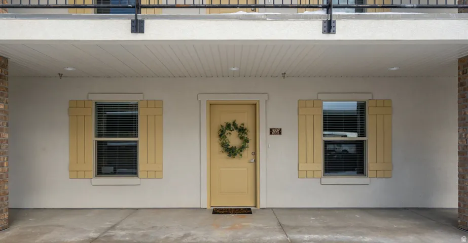 Covered entry with a pale yellow door and coordinating window shutters
