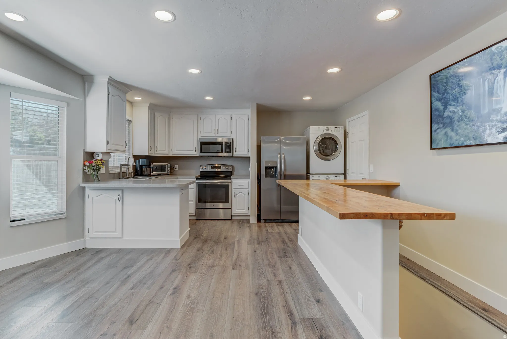 Open-concept kitchen featuring white cabinetry, stainless steel appliances, and a light-toned countertop