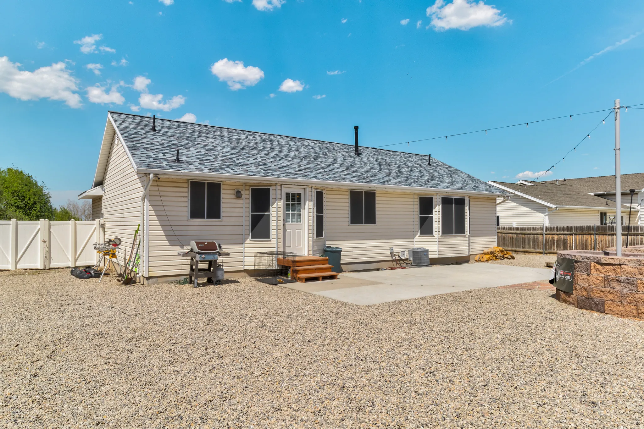 Rear exterior featuring light-colored siding, a gray shingle roof, and a concrete patio