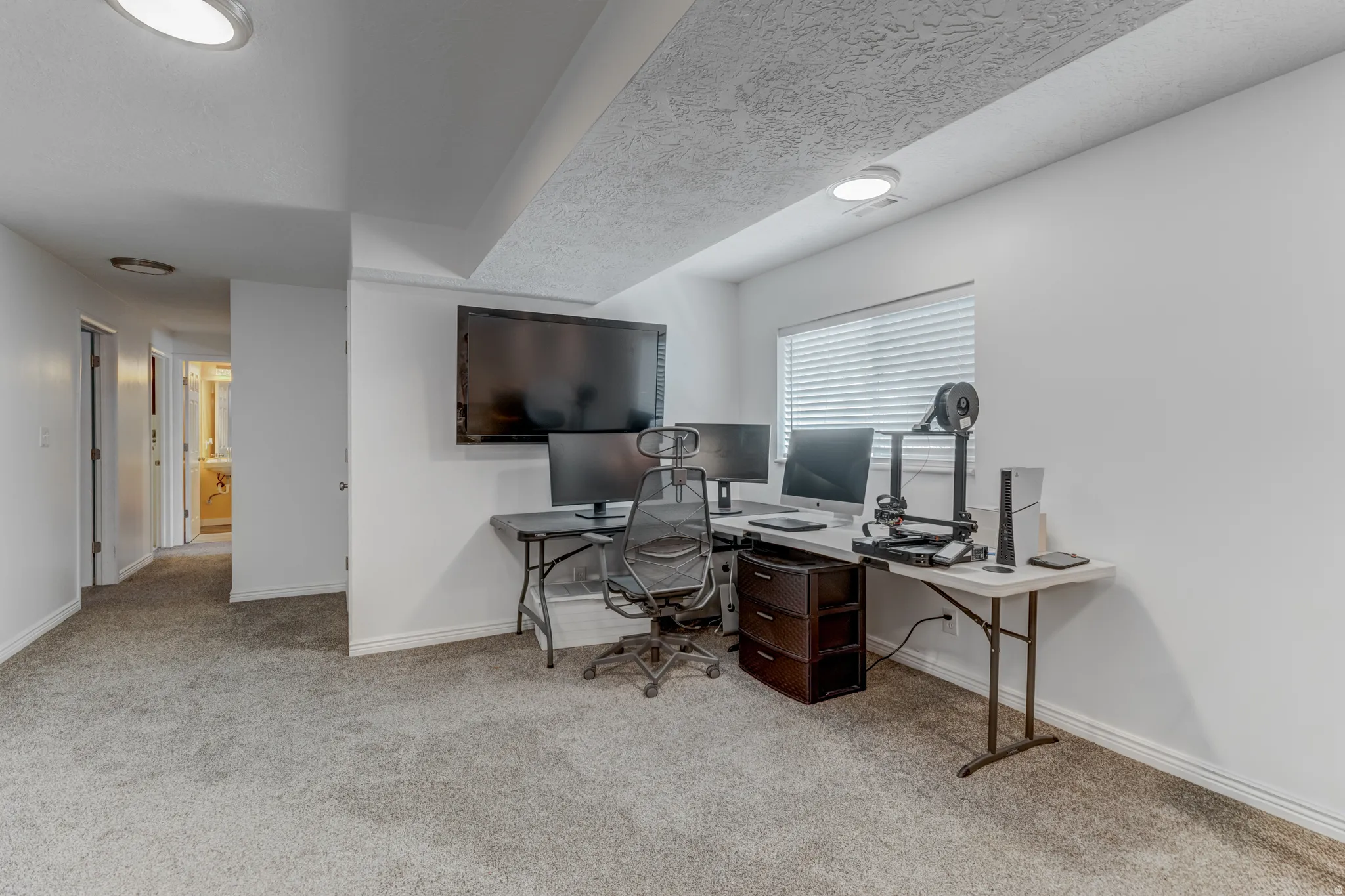 Carpeted living room with a window featuring horizontal blinds
