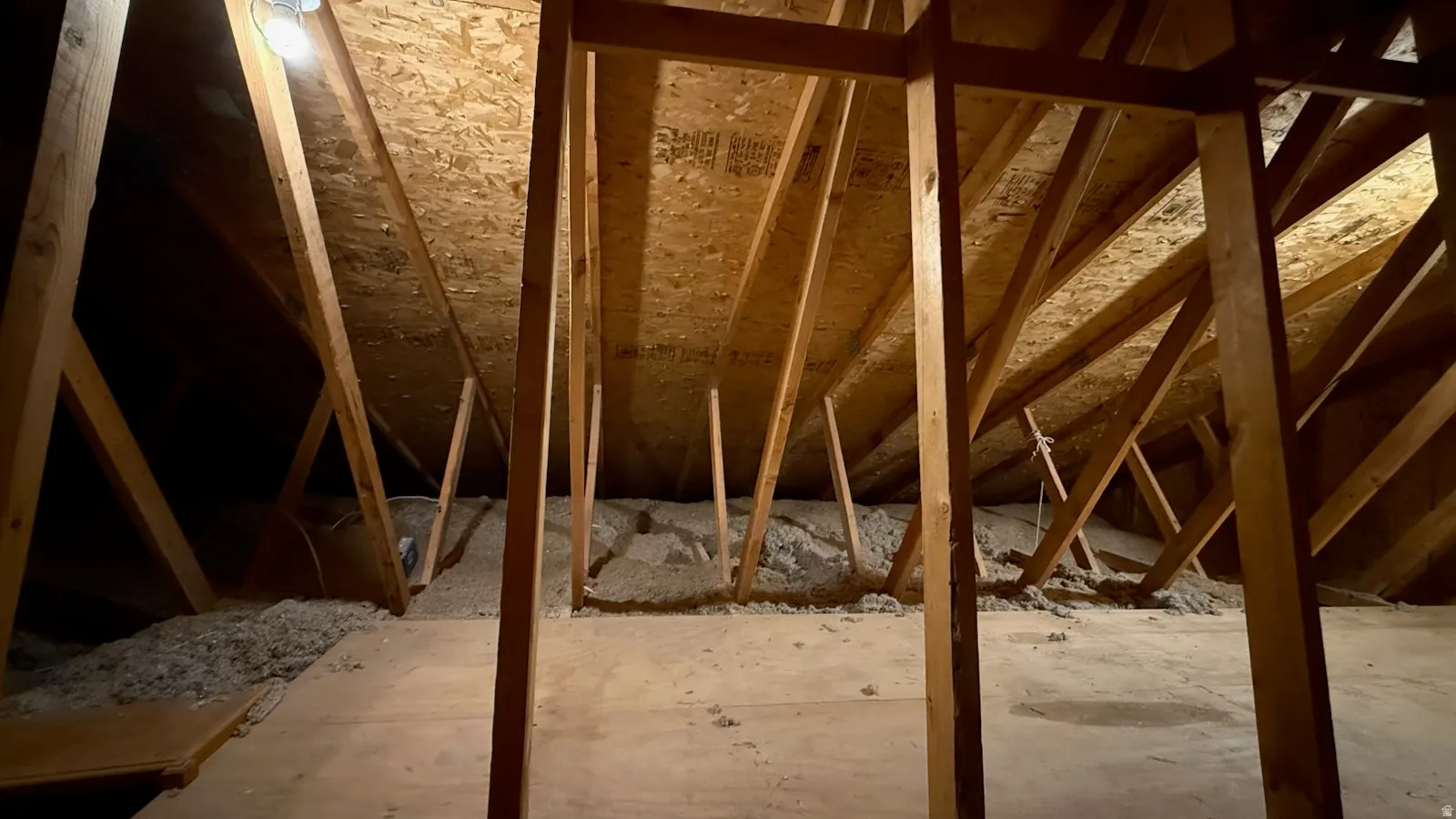 Spacious attic space featuring exposed wood rafter framing, plywood subflooring, and insulation