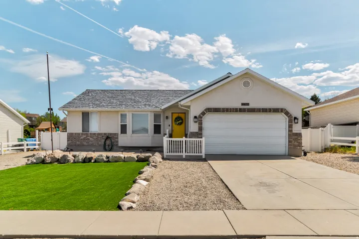 Single-story residence featuring a stucco exterior with brick accents, an attached garage, RV Parking on both sides, and a front yard with artificial turf and decorative rock landscaping