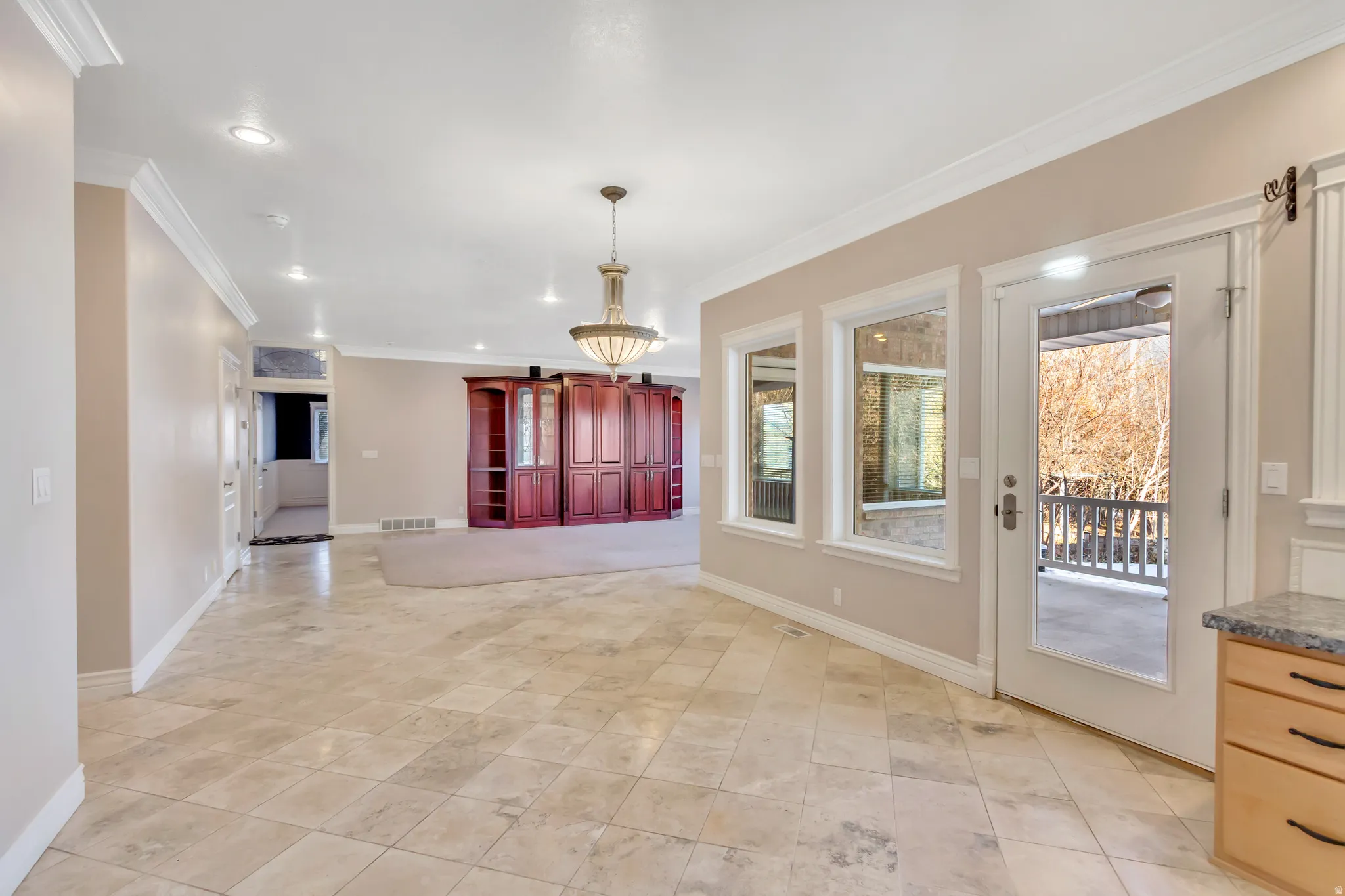 Spacious interior featuring large format tile flooring, crown molding, and recessed lighting