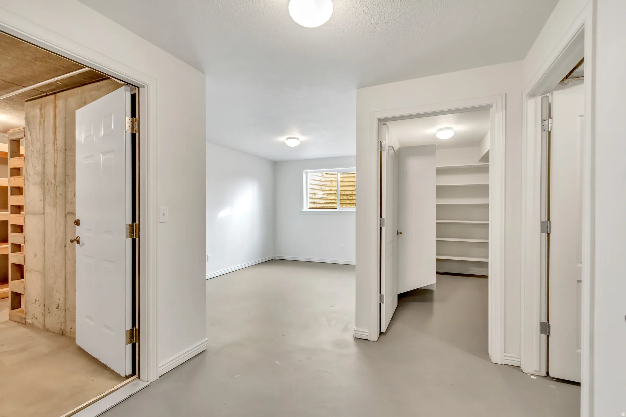 Open finished room with a window, light-toned flooring, and white walls