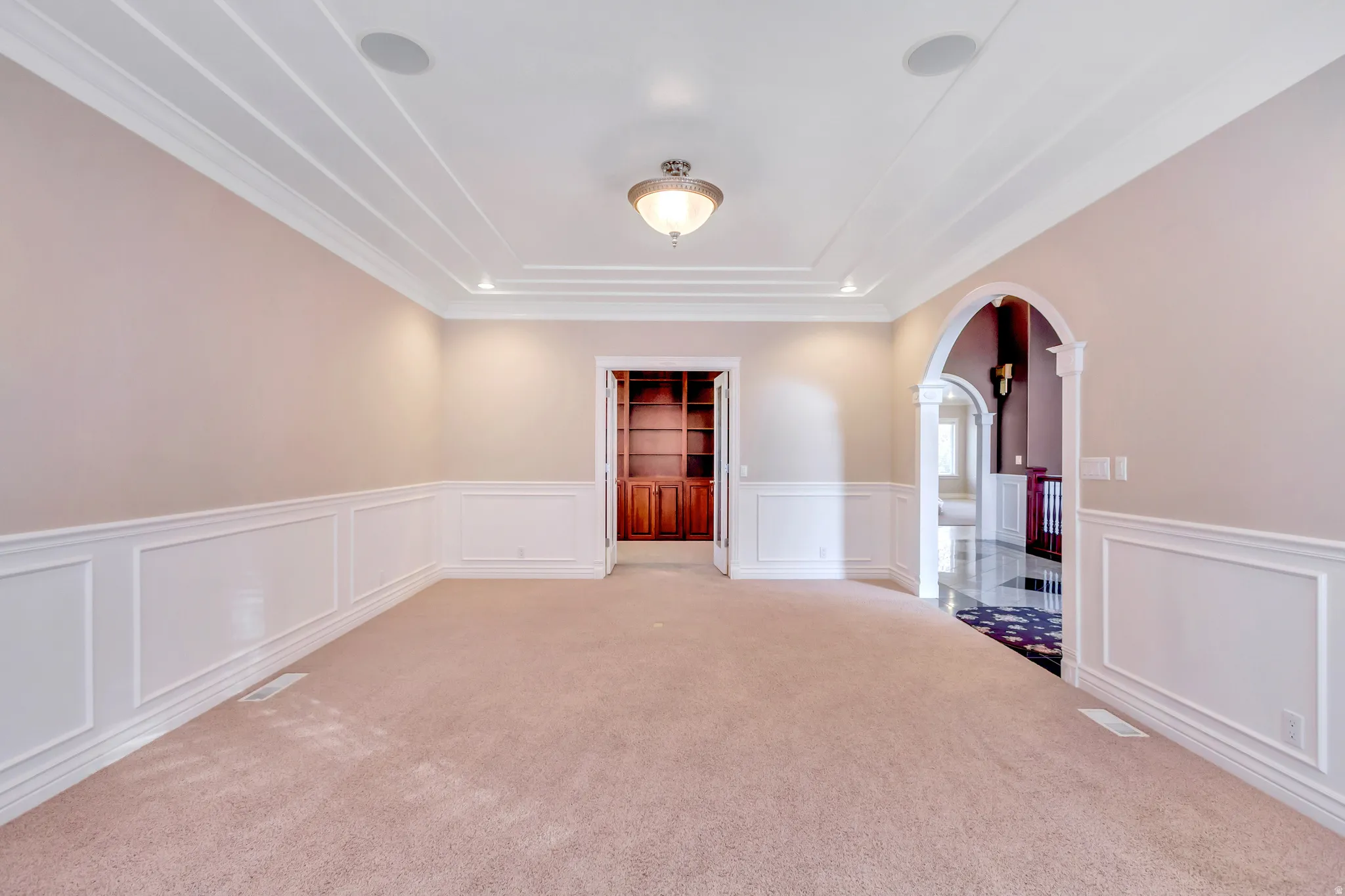 Neutral-toned room featuring a coffered ceiling with recessed lighting and built-in speakers