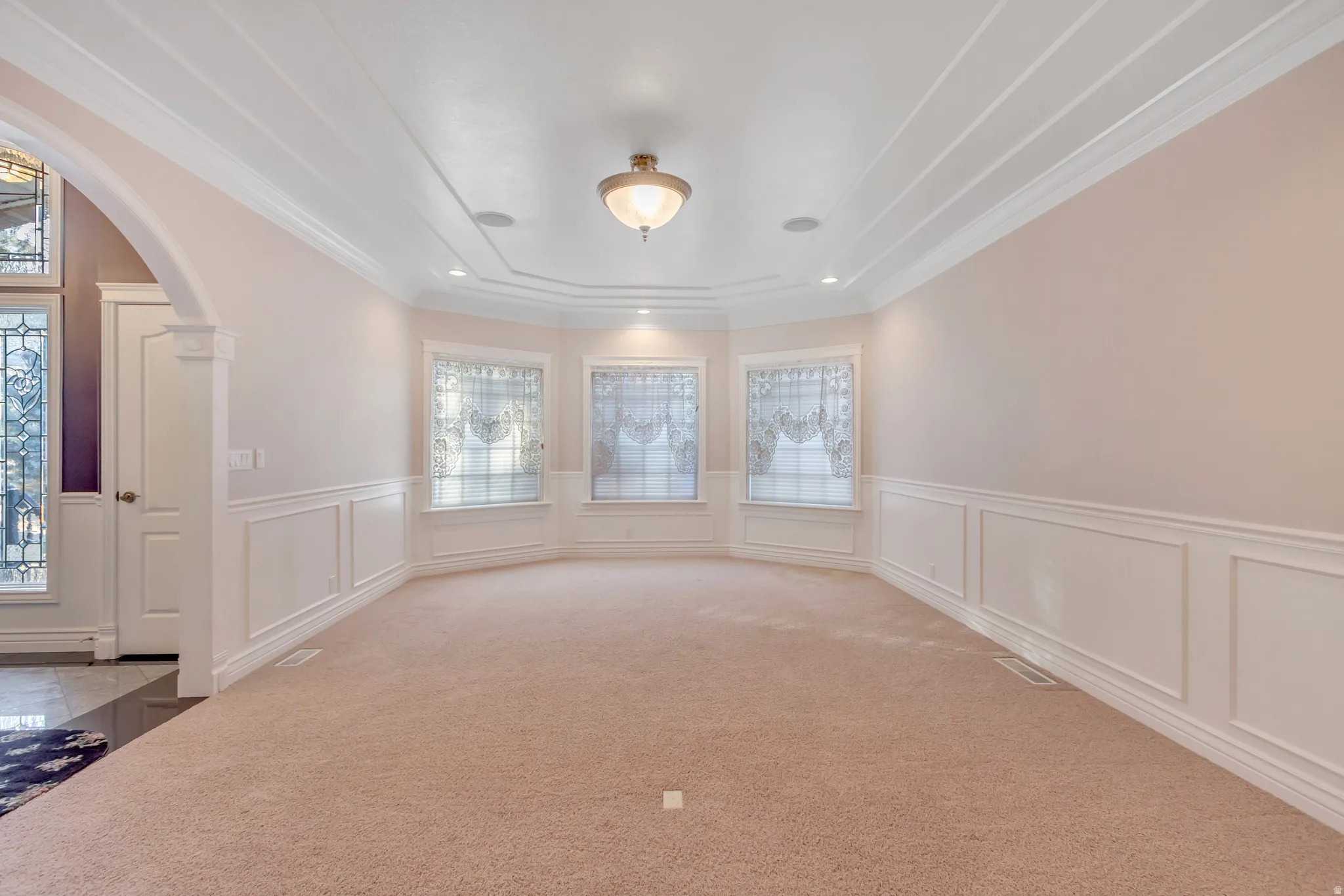 Expansive room featuring a tray ceiling with recessed lighting and a central flush mount fixture