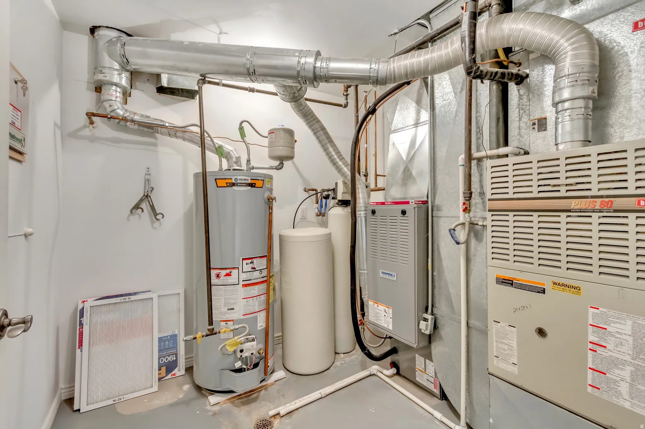 Dedicated utility room featuring a hot water heater, a water softener, and two forced-air furnaces