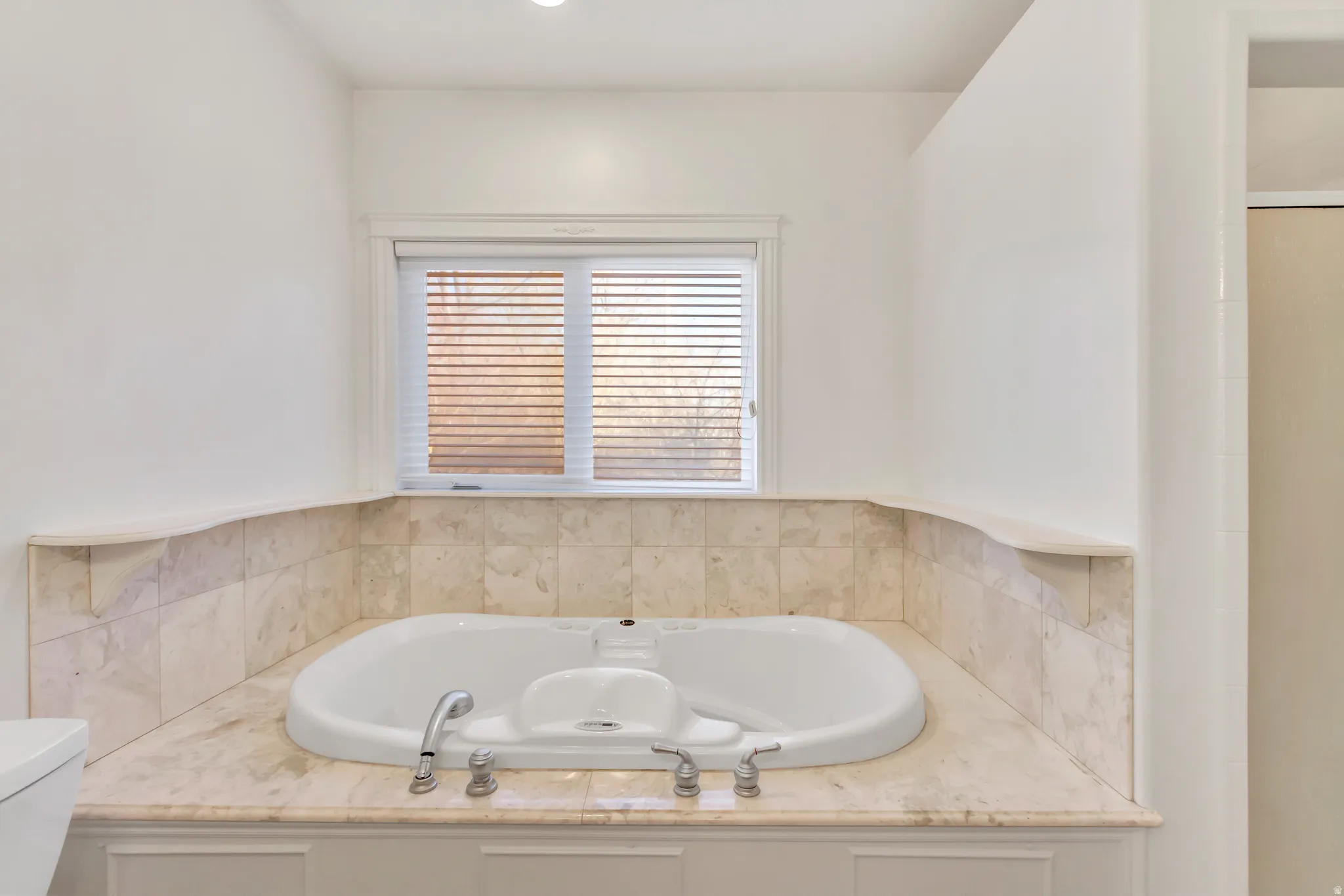 Recessed soaking tub with surrounding stone tile and countertop
