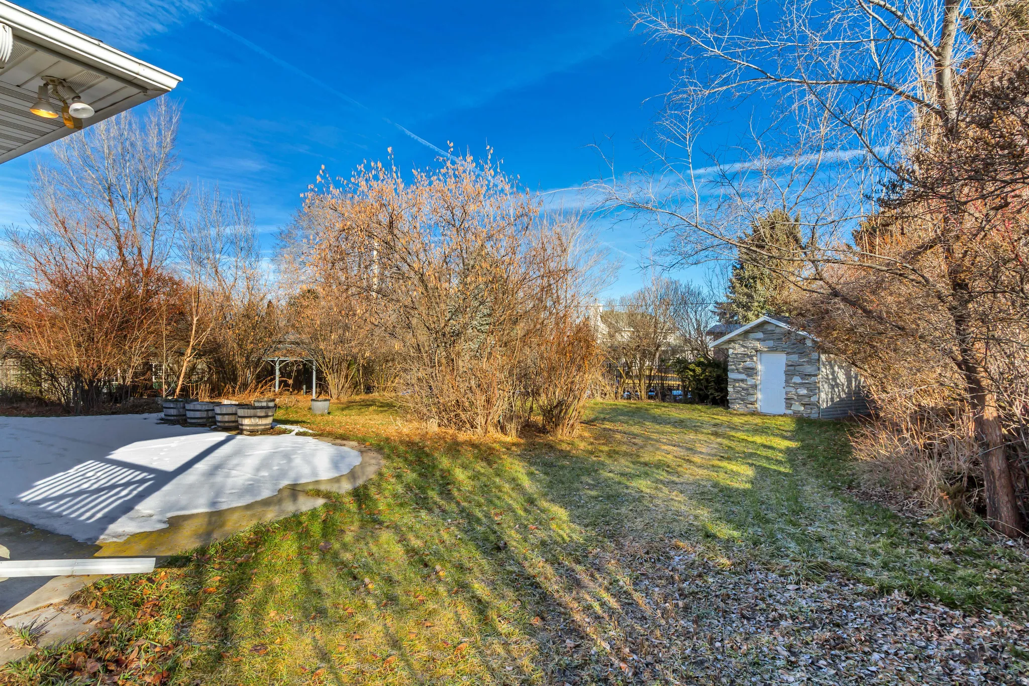Expansive yard featuring a stone-clad shed, a gazebo, and mature landscaping
