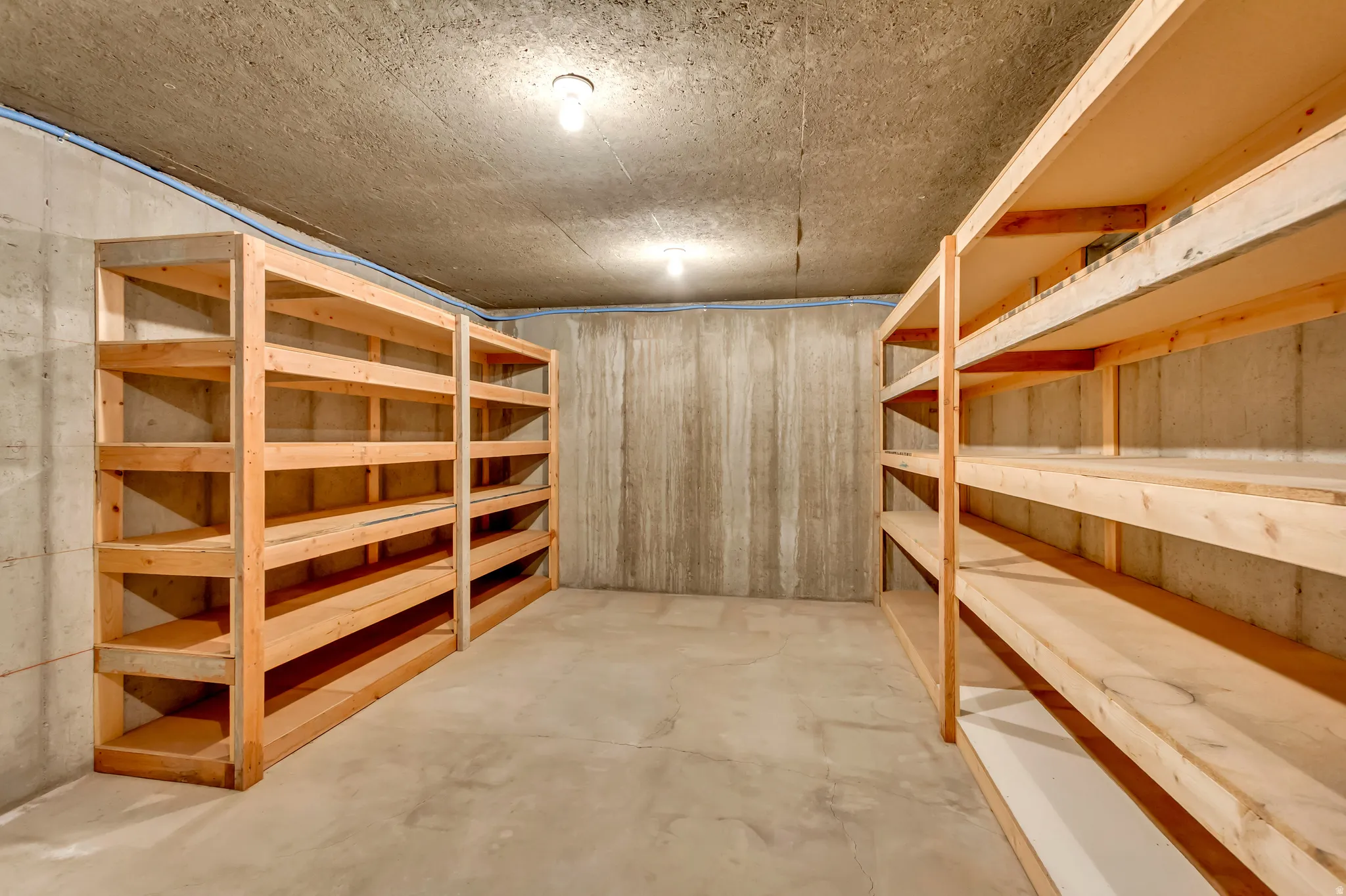 Storage area featuring concrete walls, concrete flooring, and exposed ceiling