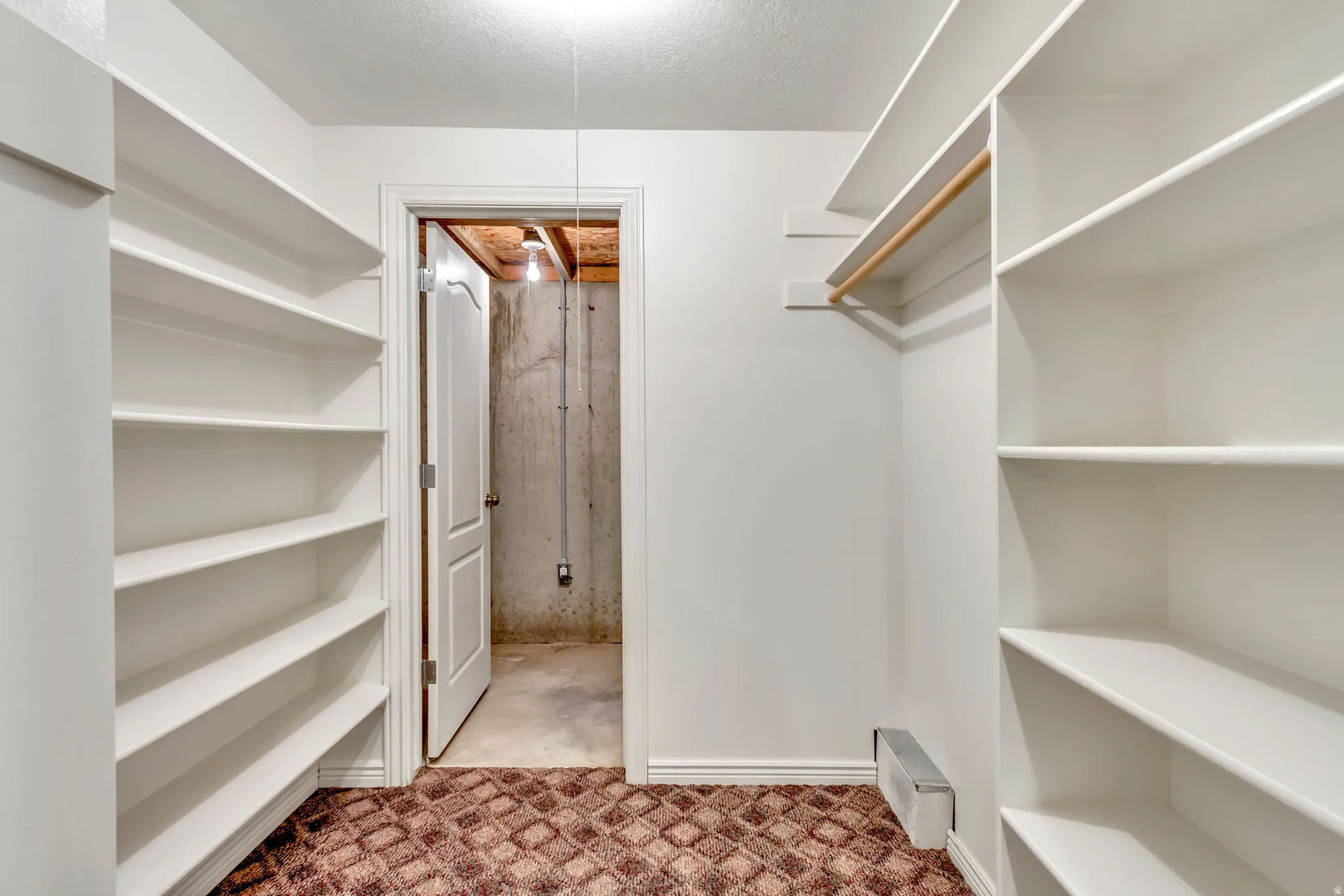Walk-in closet featuring extensive built-in shelving, white walls, white trim, a clothes hanging rod, and a patterned carpet