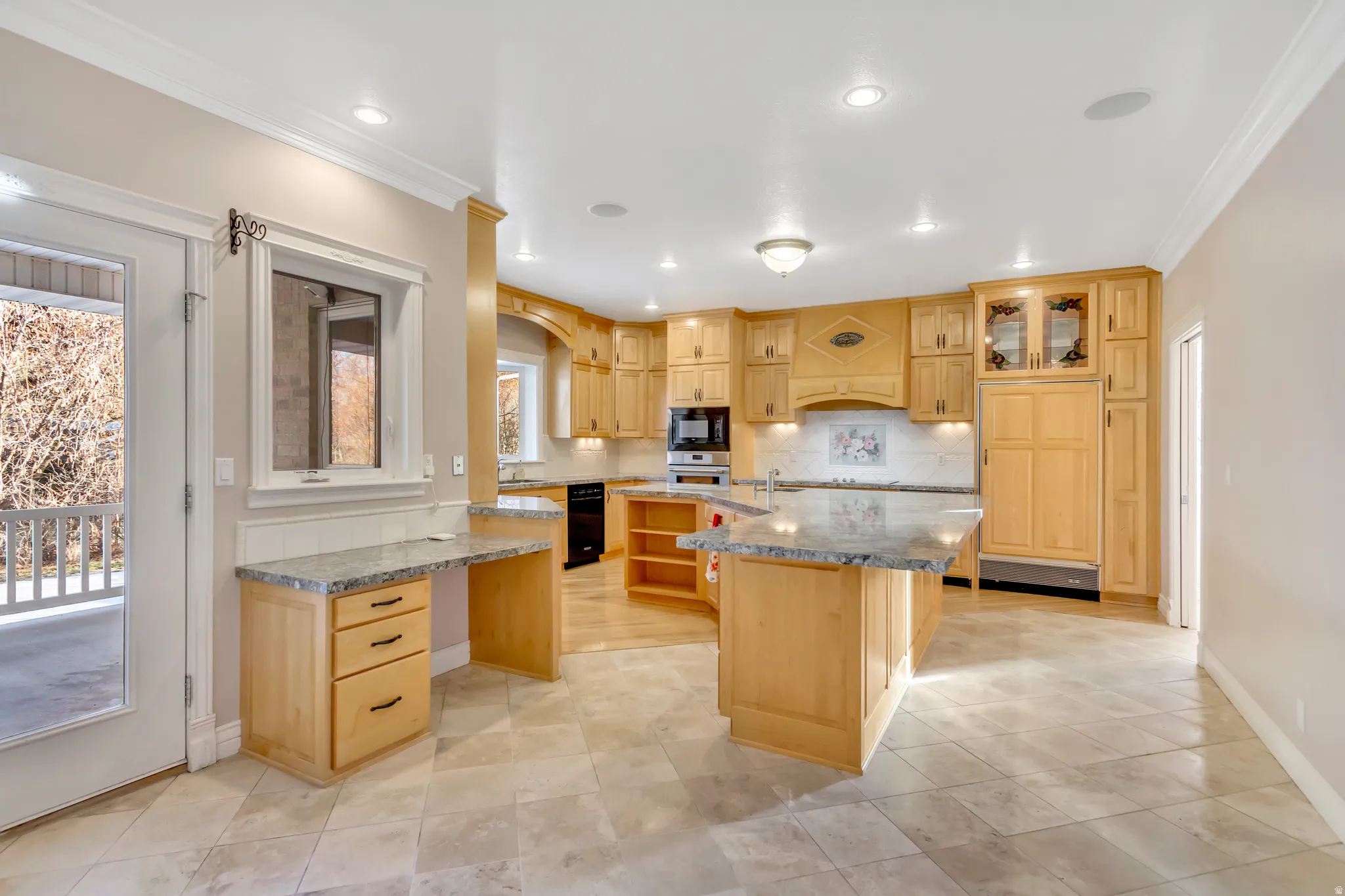 Spacious kitchen featuring a central island with a granite countertop, extensive wood cabinetry, and integrated appliances