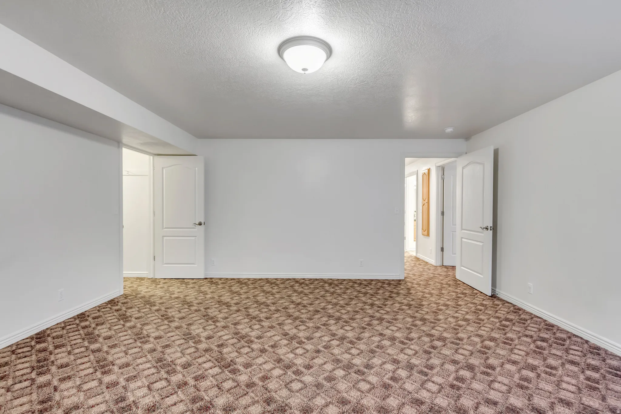 Spacious room featuring patterned carpeting, white walls, and a flush mount ceiling light