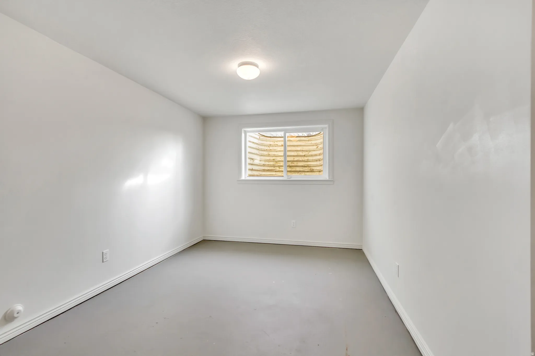 Neutral wall paint, white trim, and a window with an exterior window well
