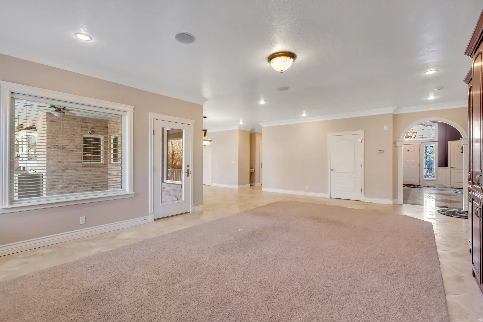 Expansive room featuring recessed lighting, a large window with horizontal blinds, and a glass-paneled door
