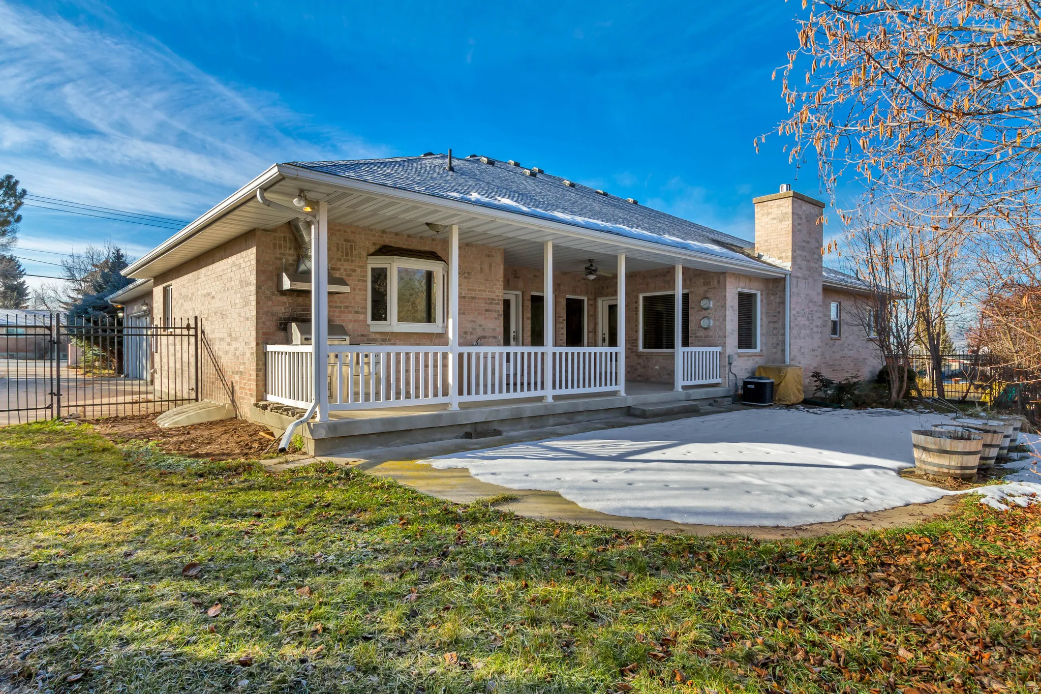 Brick exterior featuring an expansive covered patio, white railing, and a concrete patio
