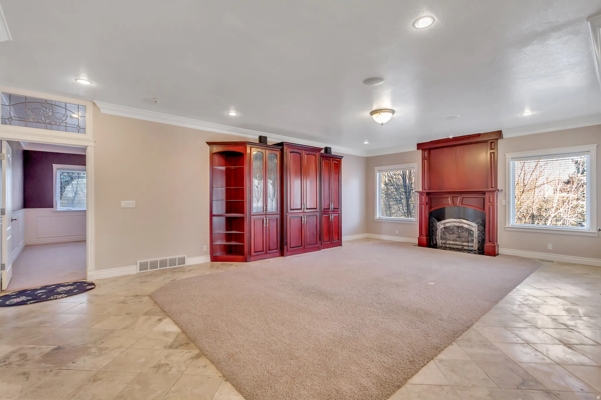 Spacious room featuring a central carpet area, tile flooring, and recessed lighting