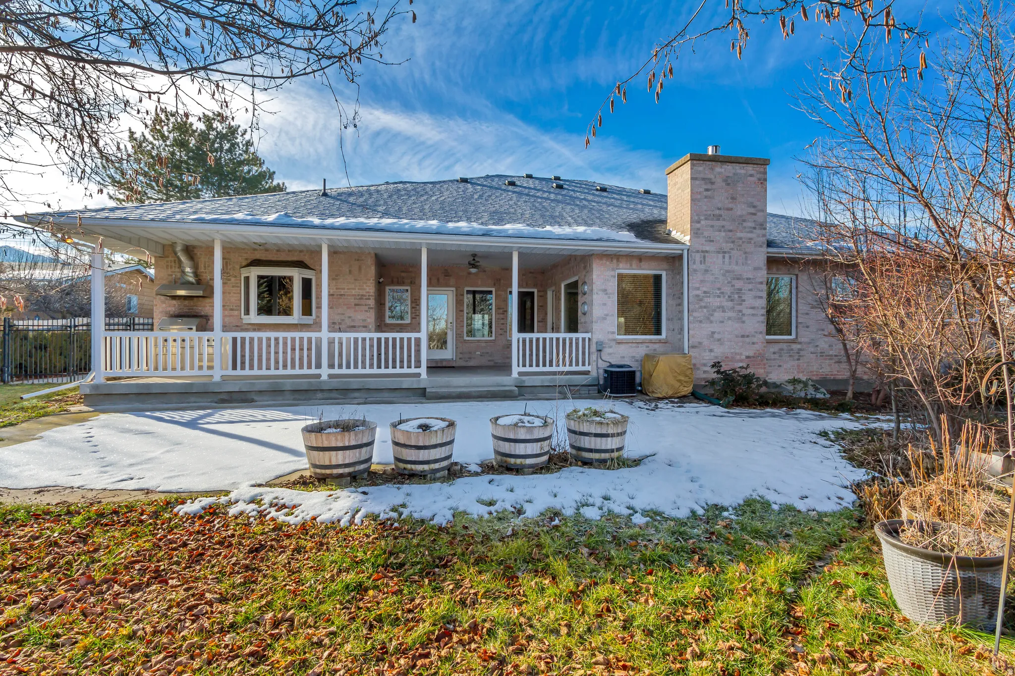 Rear brick exterior featuring a covered porch with white railing, patio, and bay window