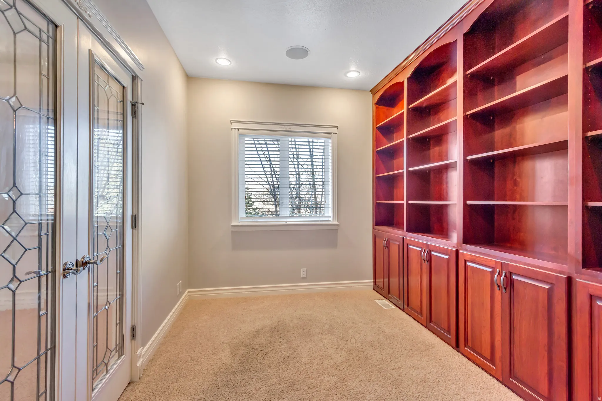Room featuring extensive built-in cherry wood cabinetry with open shelving and lower storage