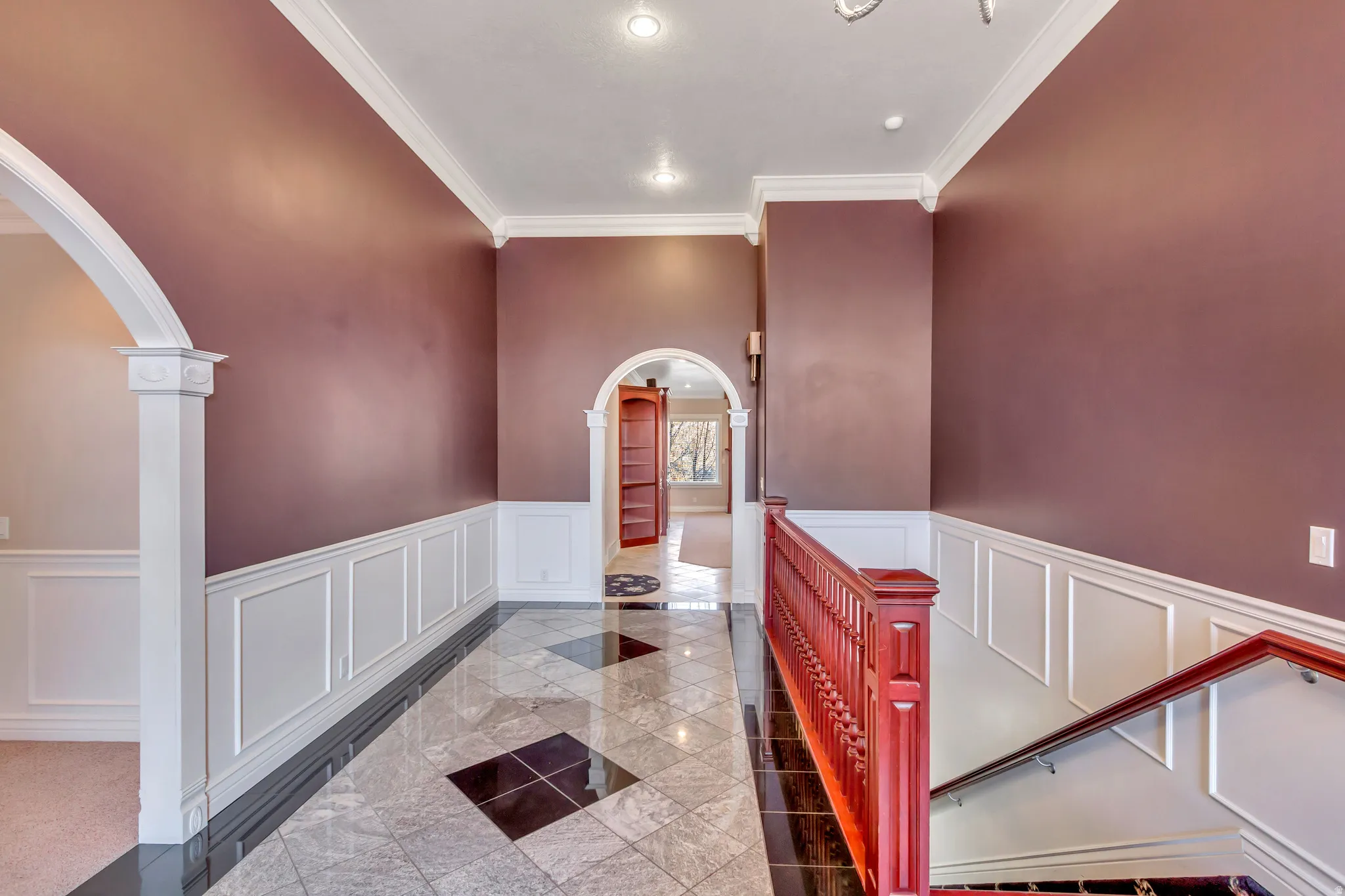 Foyer featuring a patterned tile floor, wainscoting, and crown molding