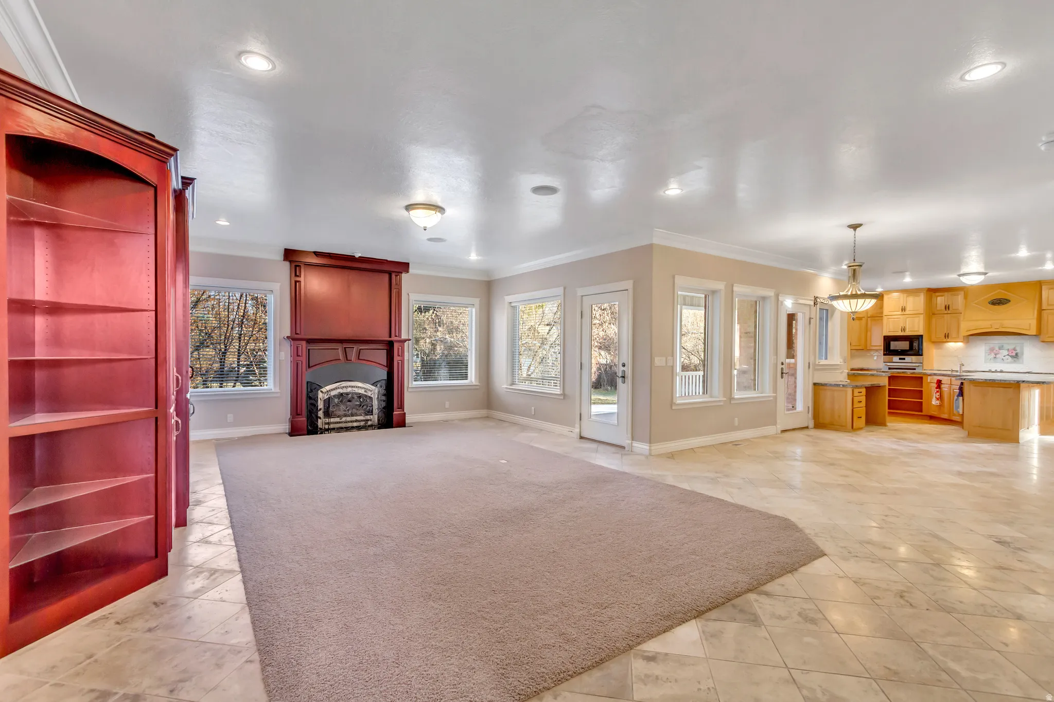 Spacious living area featuring a built-in fireplace with custom wood surround, large windows, recessed lighting, and crown molding