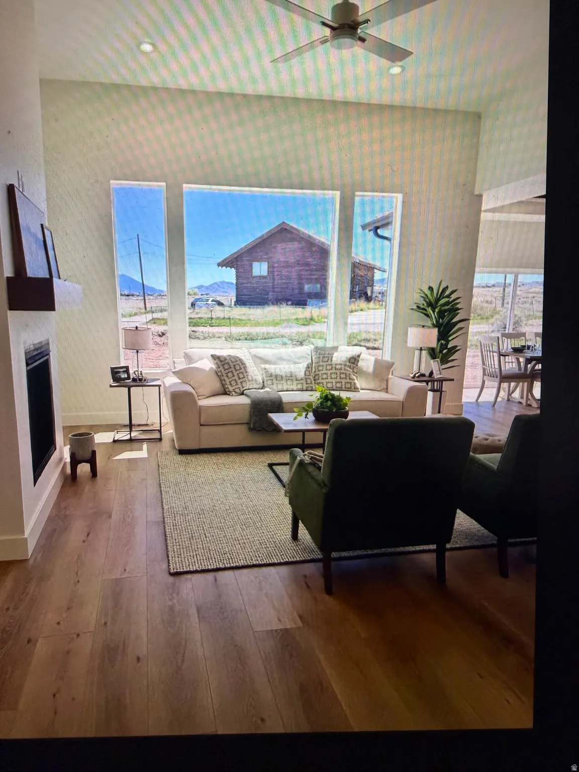Spacious living area featuring large picture windows, wood-finish flooring, a contemporary ceiling fan, and a built-in fireplace with a floating mantel