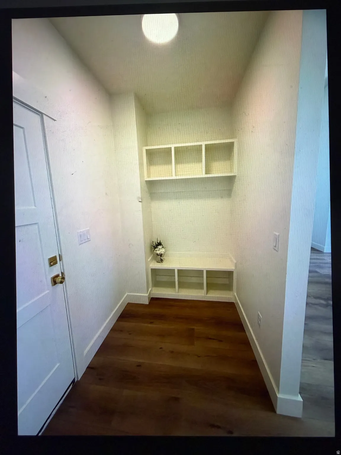 Entryway featuring built-in storage with a bench, upper shelving, and wood-finish flooring