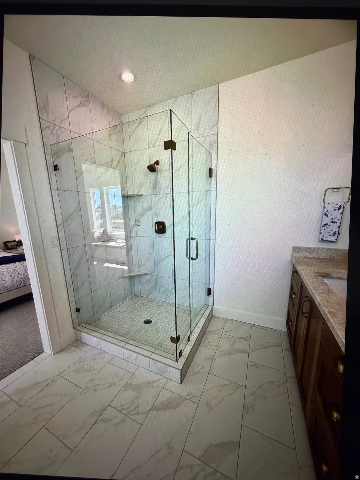 Glass-enclosed shower with full-height marble-look tile surround and built-in bench