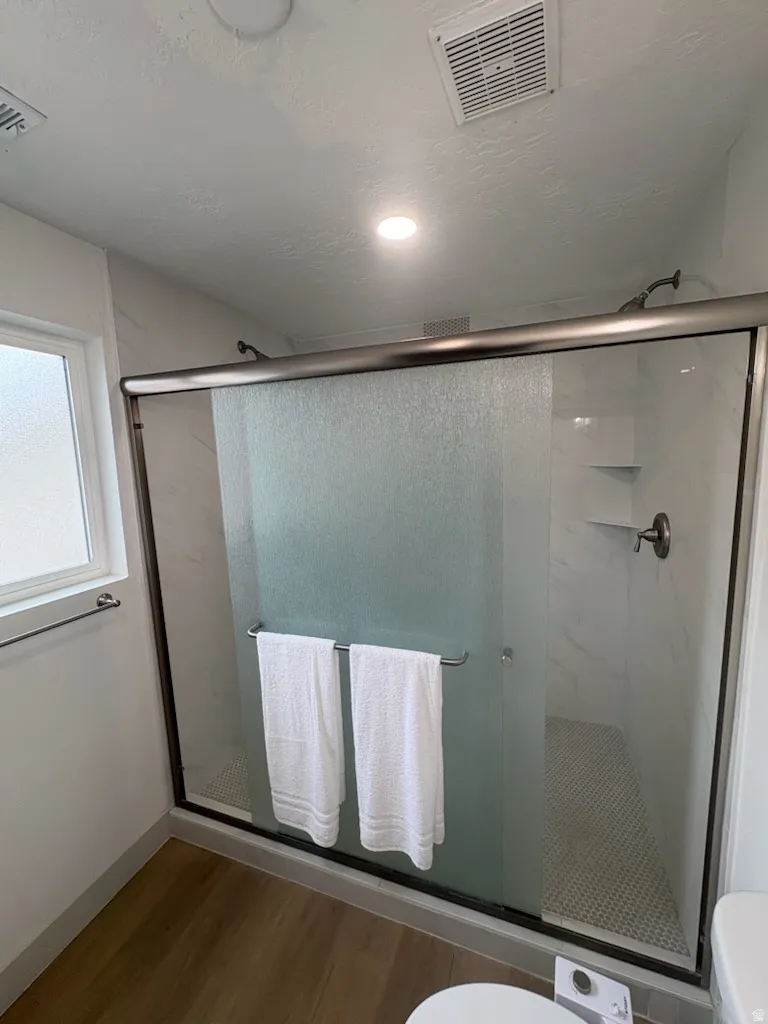 Shower enclosure featuring a framed frosted glass door, white subway tile walls, a built-in corner shelf, and a mosaic tile floor