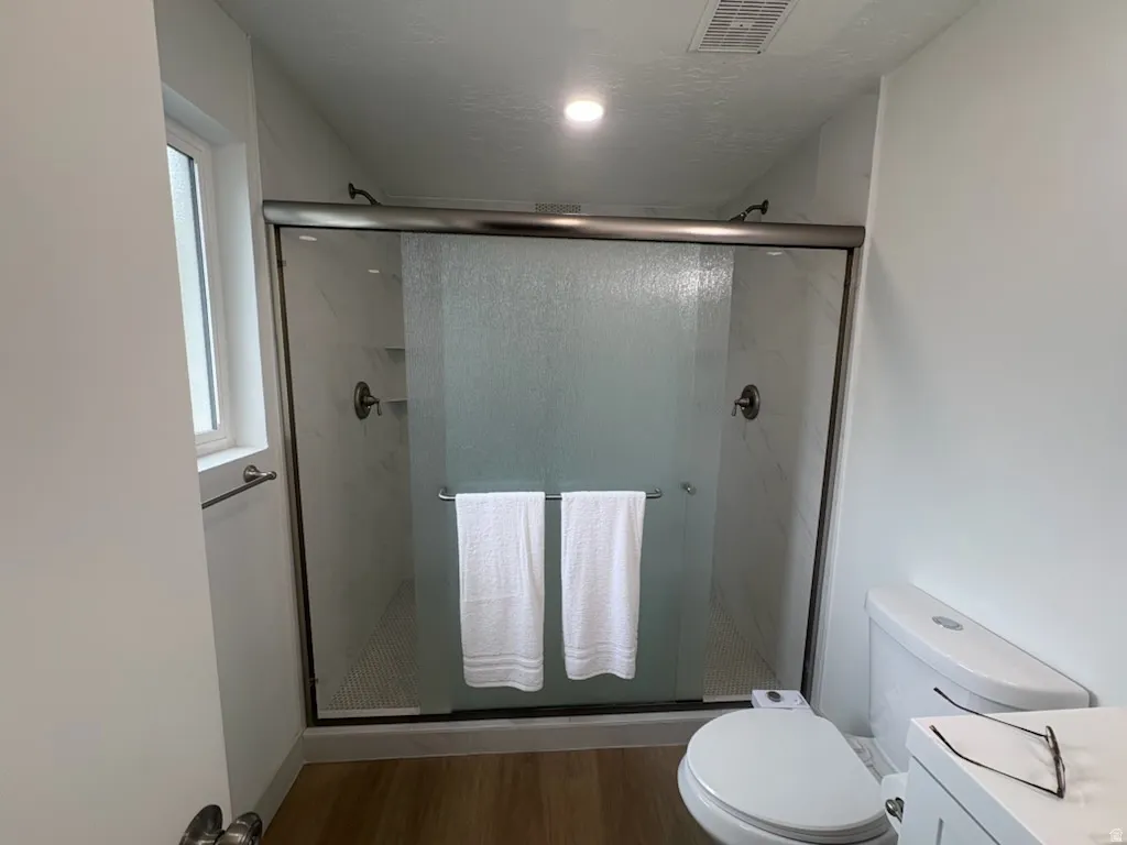 Framed shower enclosure with clear and frosted glass, featuring wall-mounted shower heads and built-in shelving