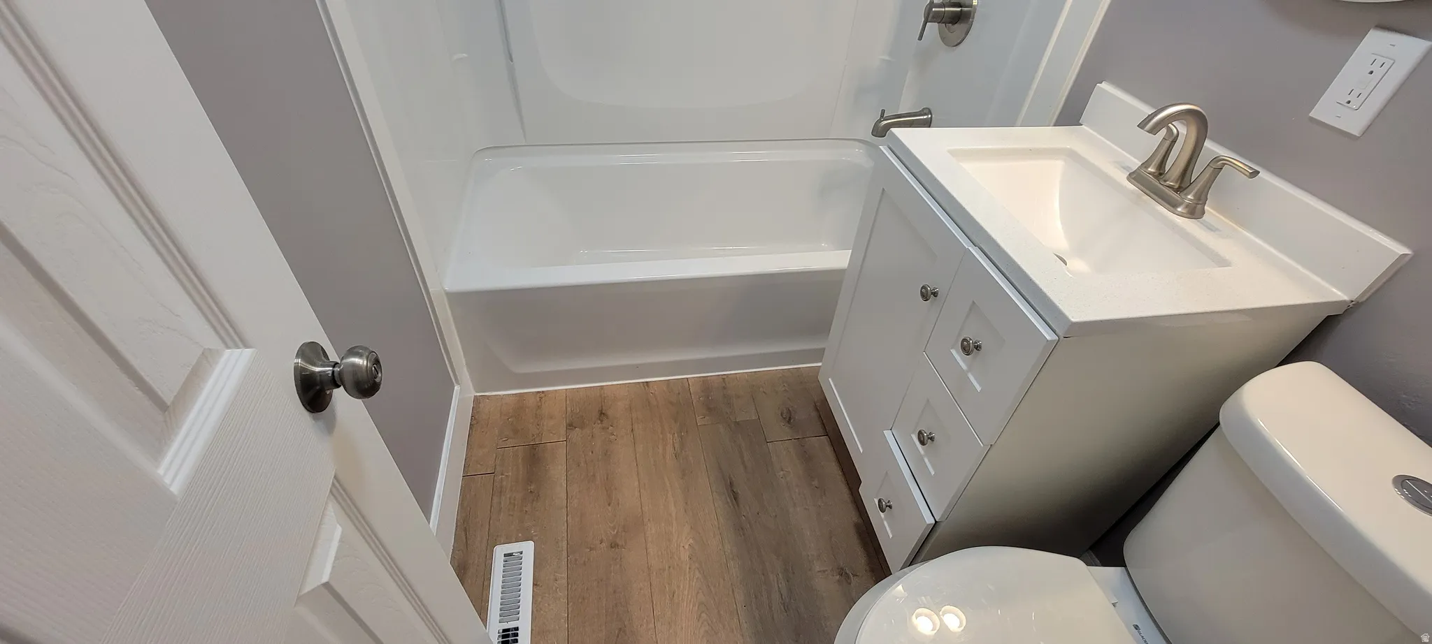Bathroom featuring a white vanity with brushed nickel hardware, integrated sink, and white countertop