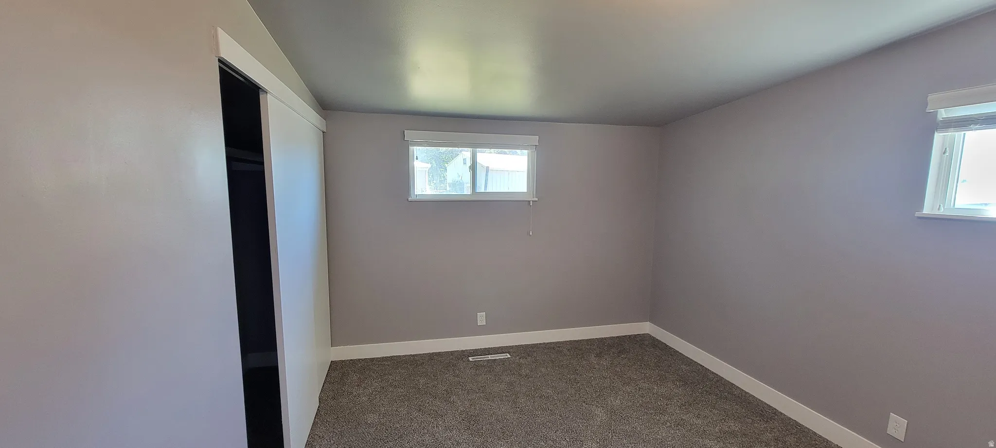 Carpeted room featuring light gray wall paint, white baseboards, and two windows with white trim