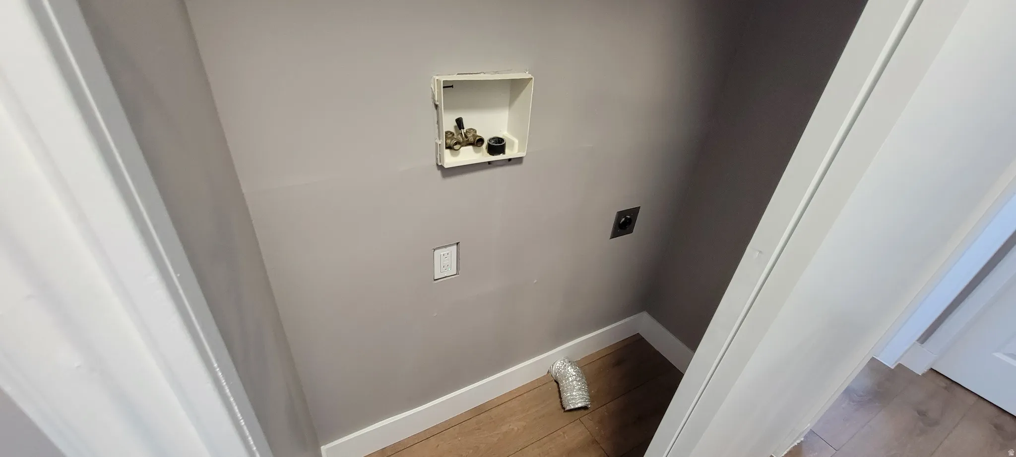Dedicated laundry alcove featuring neutral-toned walls, white baseboards, and wood-finish flooring