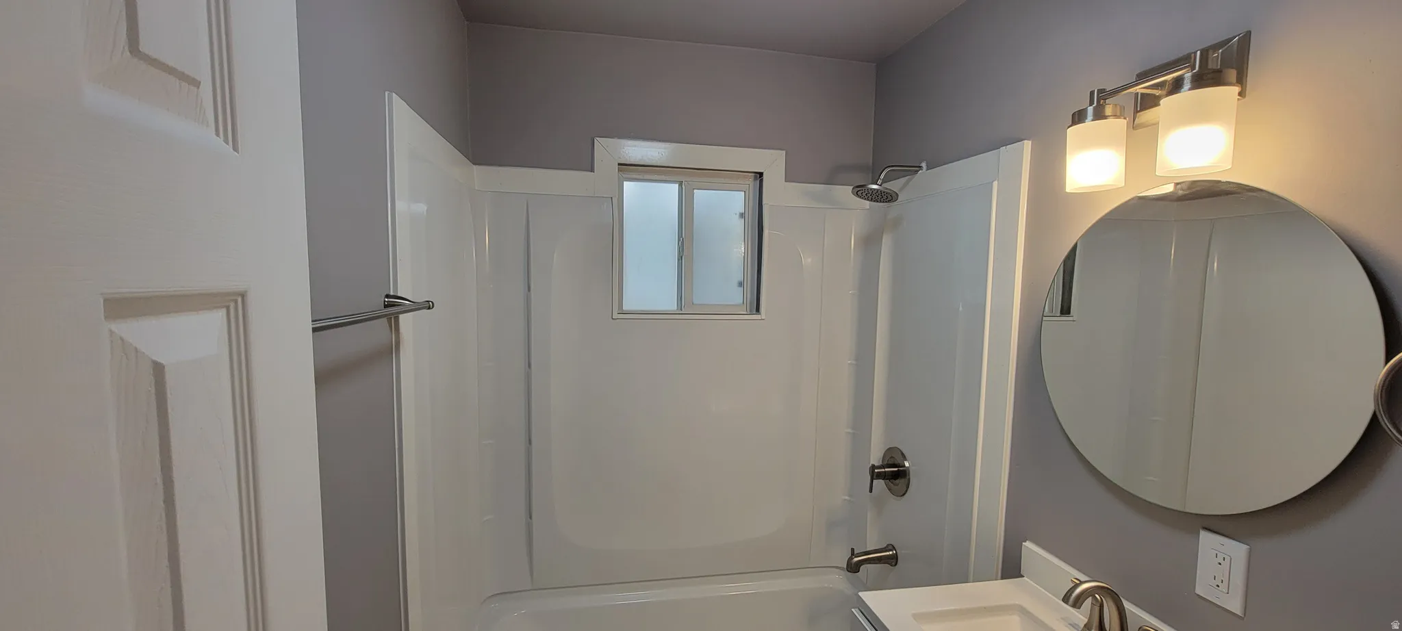 White tub and shower combination with a small window