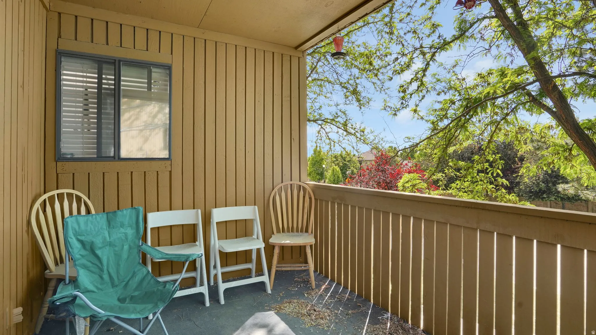 Covered outdoor patio area featuring vertical wood-paneled walls and a matching wood railing