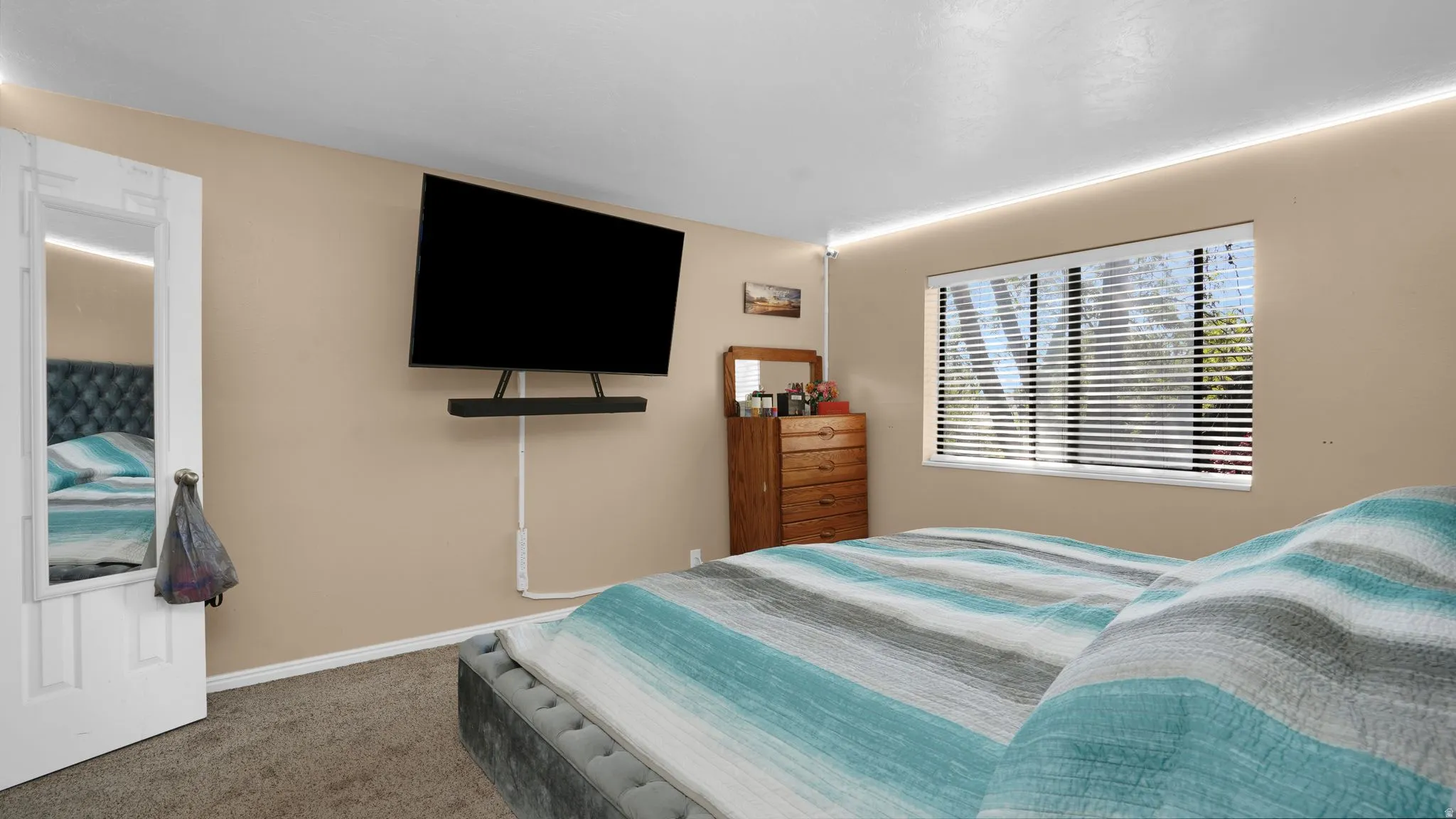 Bedroom with wall-mounted television, recessed lighting, and a window featuring horizontal blinds