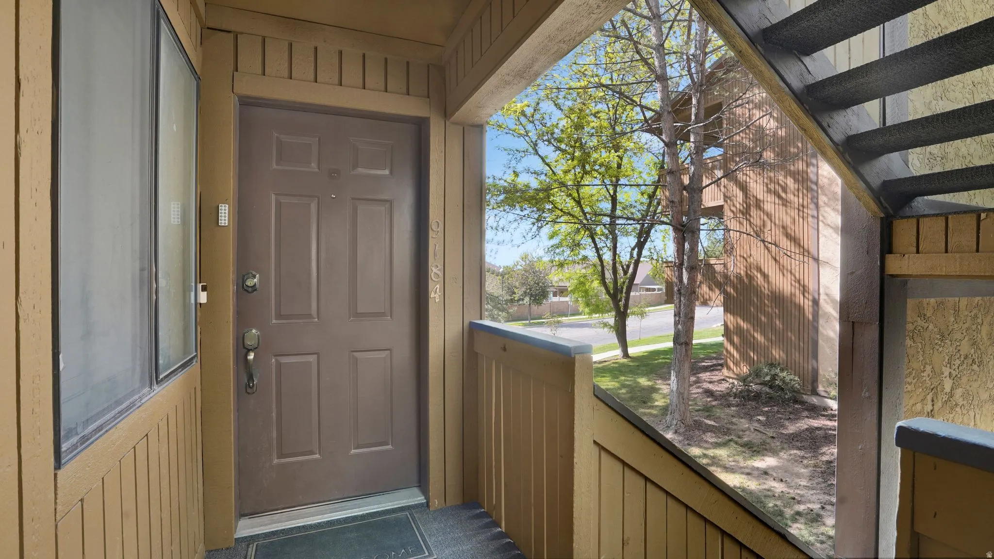 Covered entry featuring a paneled door, exterior wall sconce, and side window