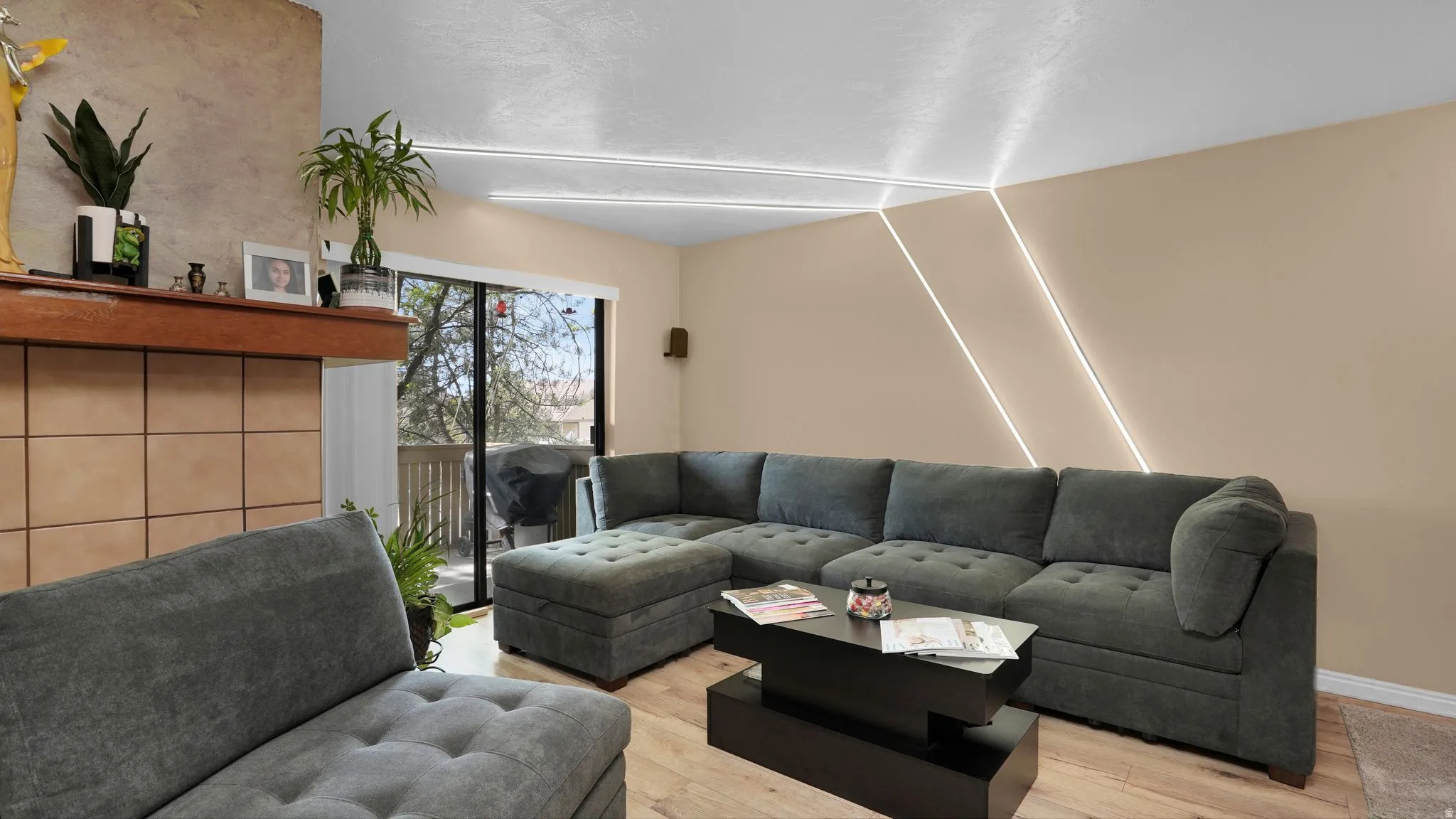 Living area featuring a fireplace with a wood mantle and tile surround, wood-finish flooring, and a sliding glass door leading to an outdoor space
